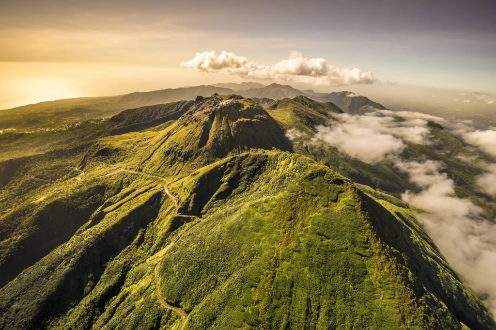 Dôme de la Soufrière vu du ciel, ses pentes vertes et ses sentiers au-dessus d'une mer de nuages
