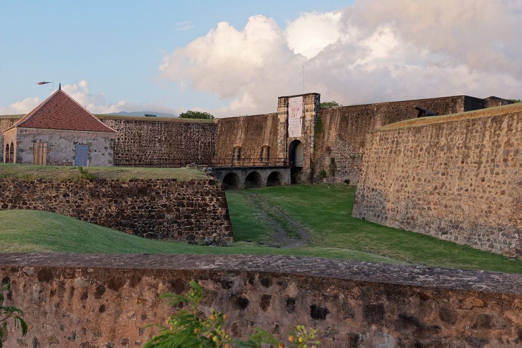 Remparts et porte d'entrée du fort Delgrès à Basse-Terre, fossé herbeux au premier plan