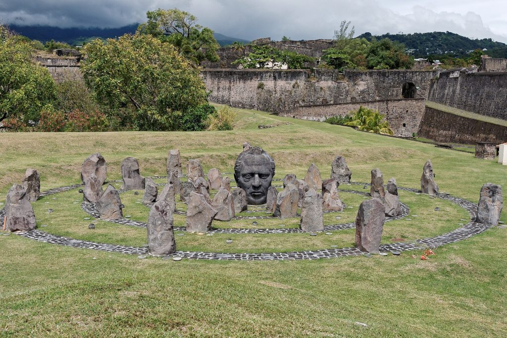 Mémorial Louis Delgrès au fort : visage sculpté entouré d'un cercle de pierres dressées