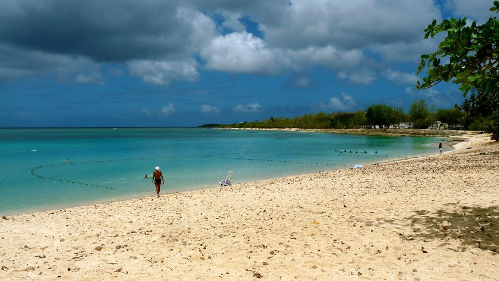 Lagon turquoise et sable clair de la plage de Port-Louis sous un ciel chargé