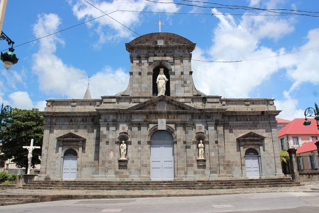 Façade en pierre de la cathédrale Notre-Dame-de-Guadeloupe à Basse-Terre, sous un ciel bleu