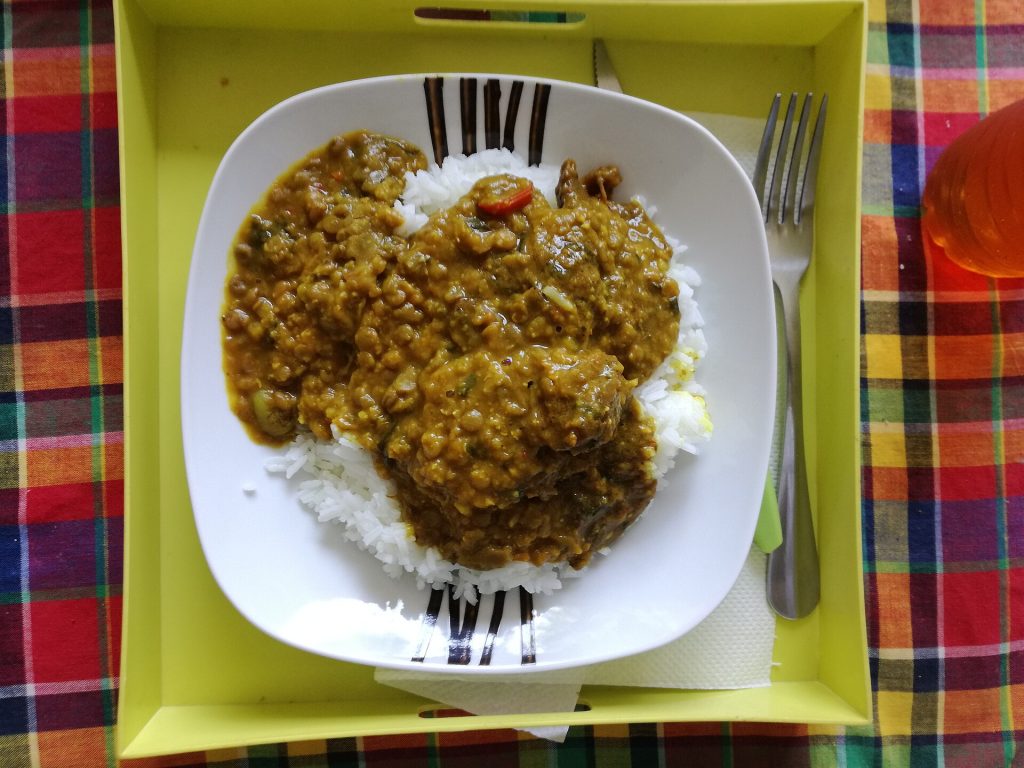 Une assiette de colombo de poulet et de riz sur un set en madras
