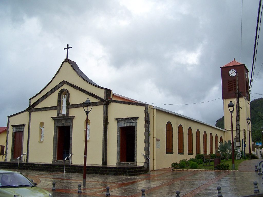 Église Saint-Augustin de Saint-Claude, façade claire et clocher-tour, sous un ciel nuageux