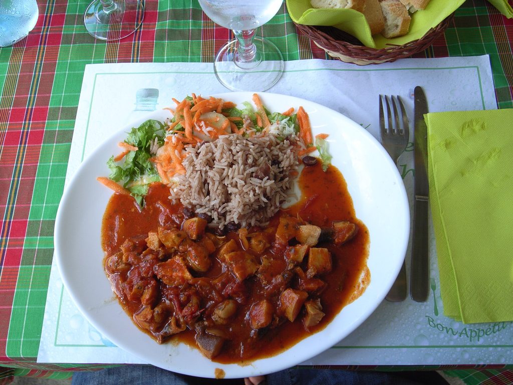 Une assiette de fricassée de lambi servie avec du riz et des crudités