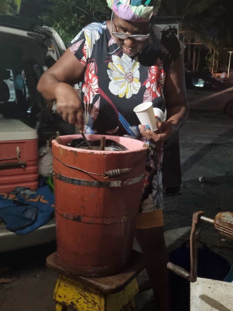 Une marchande tourne la sorbetière à manivelle du sorbet coco, à Sainte-Anne
