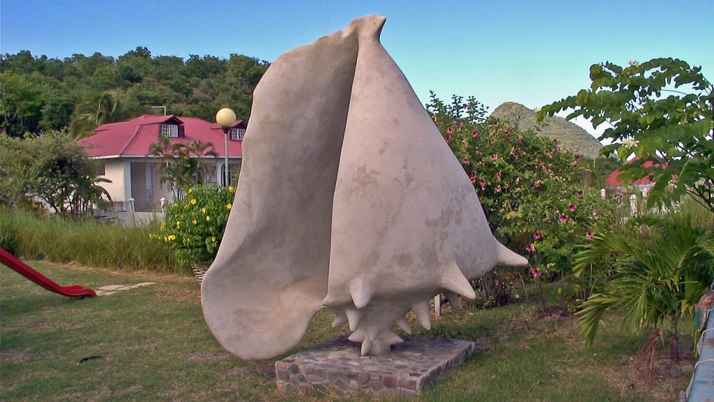 Une sculpture de conque de lambi géante dans un jardin de Guadeloupe