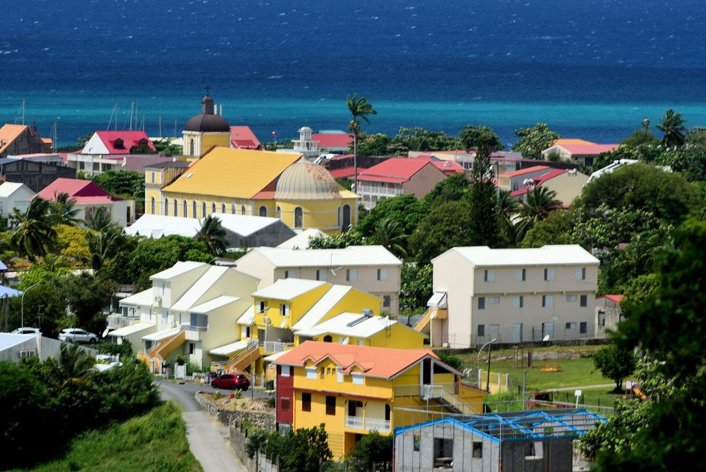 Église jaune de l'Immaculée-Conception et maisons colorées de Grand-Bourg face à la mer