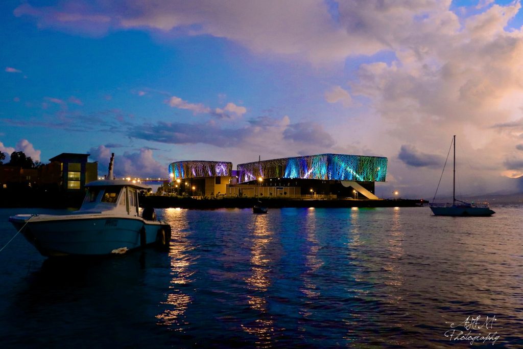 Mémorial ACTe illuminé à la tombée de la nuit, reflété dans l'eau du port de Pointe-à-Pitre