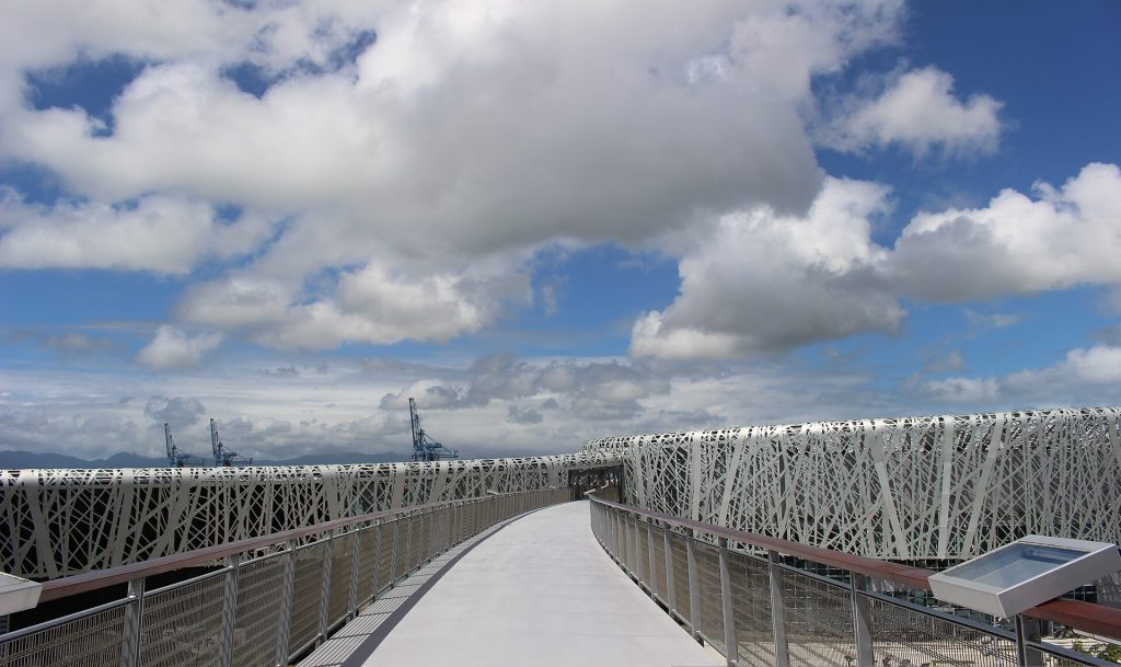 Passerelle piétonne menant au Mémorial ACTe, avec les grues du port de Jarry au loin