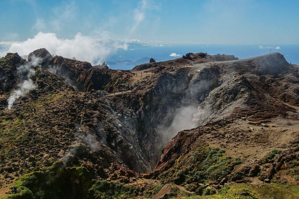 Plateau sommital de la Soufrière : cratères fumants et roche nue, la mer à l'horizon