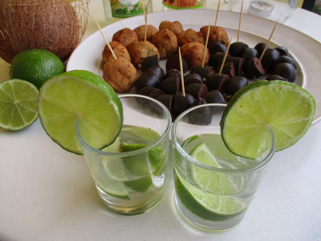 Deux ti-punchs au citron vert devant une assiette d'accras et de boudin